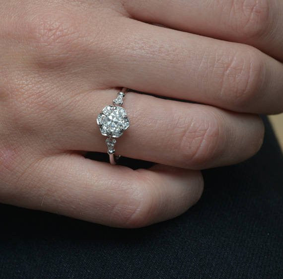rose gold round halo flower engagement ring with band in a hand