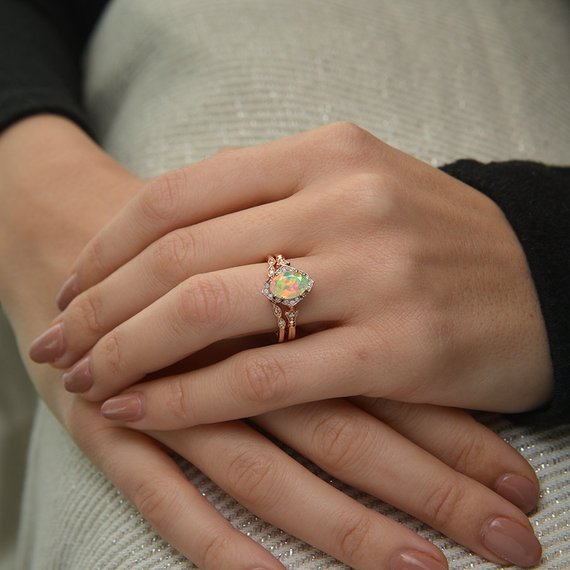 oval opal engagement ring in rose gold in a hand